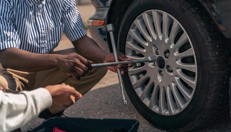Man changing a tire on the road