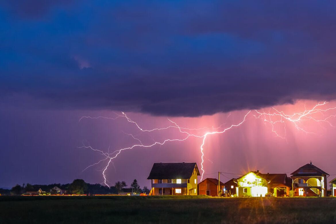 Lightning storm over coastal homes at night, the kind of severe weather Texas windstorm insurance protects against