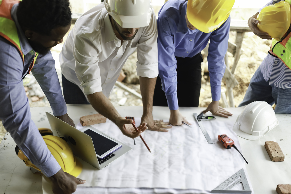 Workers and project managers on a construction site reviewing plans and documents