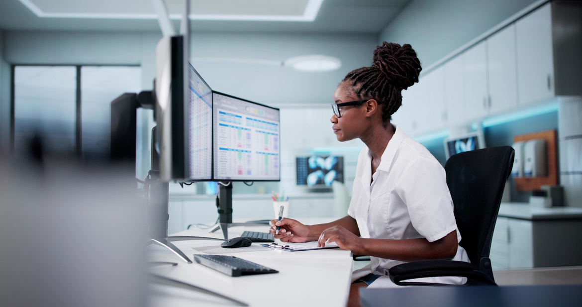 A nurse works on a computer at a nurse’s station, representing cyber liability for healthcare professions