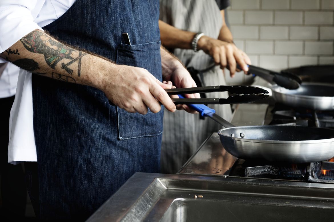 Line cooks working in a commercial kitchen during dinner service at a full-service restaurant, representing the need for restaurant insurance