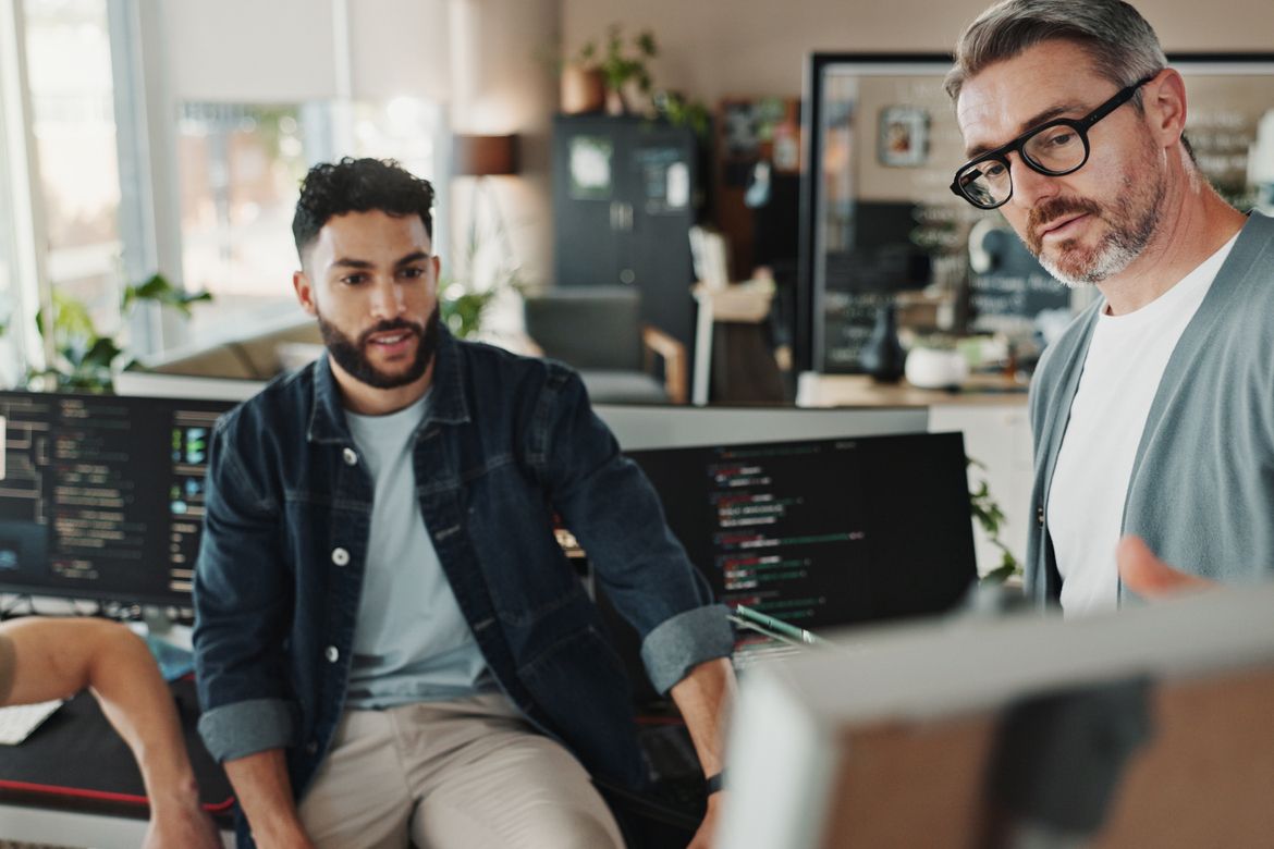A SaaS startup team reviews code and insurance contracts at a standing desk workspace